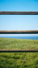 Valla de postes de madera en pradera de hierba junto al mar