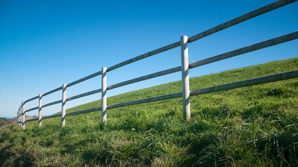 Valla de postes de madera en colina de hierba verde