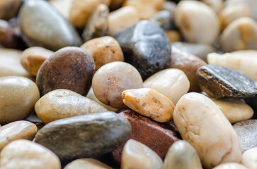 A horizotal image of smooth, tumbled rocks in a variety of colors.