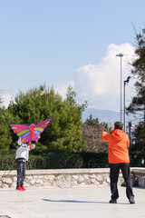 Father and son flying a kite into the sky. Blue sky. Sports kite festival. Clean Monday in Greece. A flying kite with a wriggling tail. Copyspace, banner