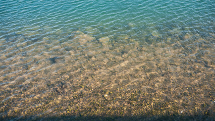 Superficie de agua de una ría y piedras en el fondo