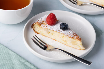 Slice of apple pie with powdered sugar, garnished with raspberries and blueberries
