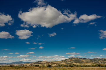 Italian country landscape with hills in the background and blue sky with withe clouds