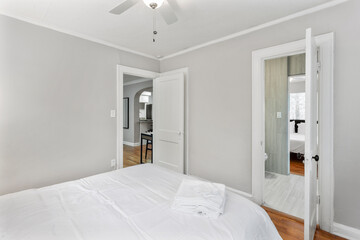 Comfortable bed, dry reeds and chest of drawers near white wall