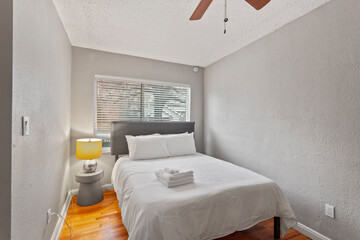 Comfortable bed, dry reeds and chest of drawers near white wall