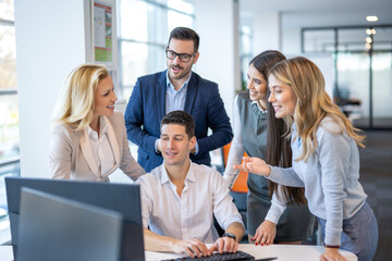 Group of successful company employees working together and having a meeting near computer in modern office.