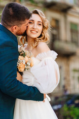 the groom gently hugs and kisses the bride.