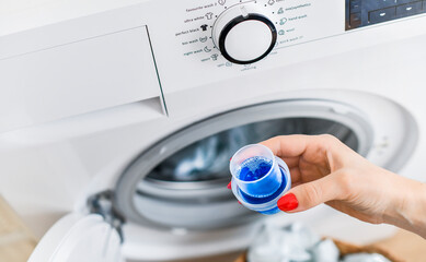 Woman hand using or filling detergent into wash machine