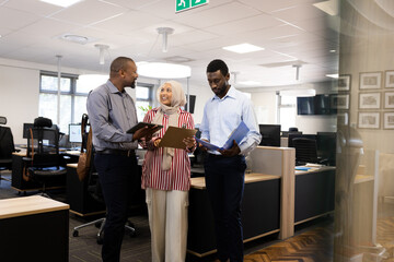 Happy diverse female and male businesspeople talking and working in office