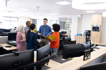 Happy diverse female and male businesspeople talking and working in office