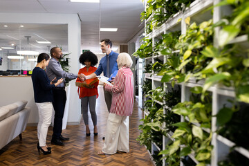 Happy diverse female and male businesspeople talking and working in office