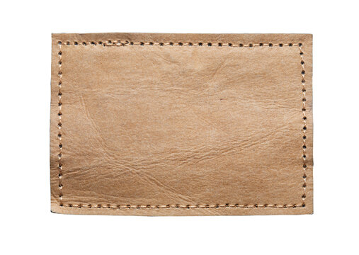 Blank brown leather label on white background, macro close up. Synthetic leather patch with stitching