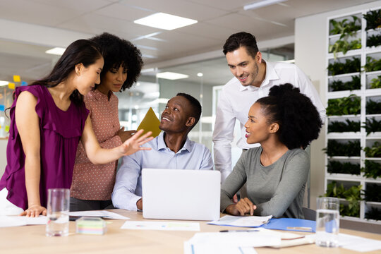 Diverse Female And Male Businesspeople At Desk Talking And Working In Office