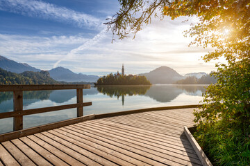 Wooden walkway around the popular Lake Bled in Slovenia. Path with a view of the beautiful church on the island during the sunrise.