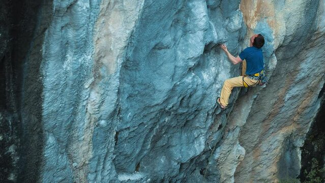 Strong rock climber lead climbing on overhanging rock face, rock climber making a big move, cinematic slow motion rock climbing