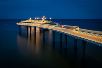 The new modern pier in Koserow, Usedom, northern Germany, opened in 2021, lit during the blue hour after sunset - 572788712