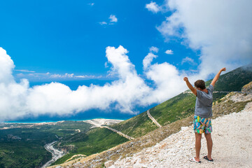 Naklejka premium Young guy near Llogara Pass. White fog high in the mountains. View from highlands on the serpentine road. Albania.