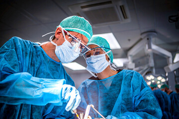 Two surgical residents holding retractors and scalpels during a surgical simulation lab