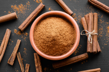 Cinnamon sticks and cinnamon powder on dark rustic background, healthy spice, (Cinnamomum)
