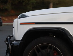 Fototapeta premium Brandless white offroading luxury vehicle. Closeup of white car, SUV crossover. Sleek elegant modern car wallpaper background image closeup, modern cars. Parked car in parking lot at sunset.