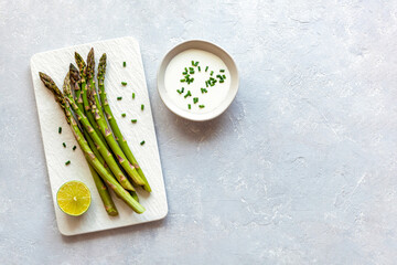 Asparagus stems on the rectangular plate served with green lemon and parsley