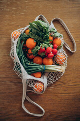 Fresh fruits and vegetables in the string bag on the wooden table
