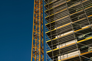 building with scaffolding and cranes, the facade of the house is clad with galvanized steel...