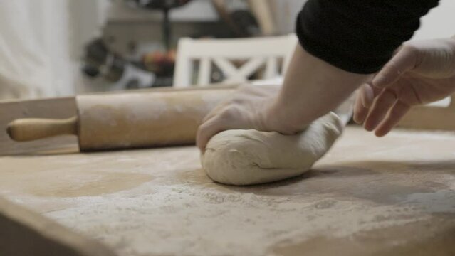 Hands knead a bread dough on a vintage baking table