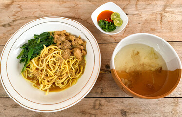 Noodle chicken soup (mie ayam) Indonesia food served on wooden table.