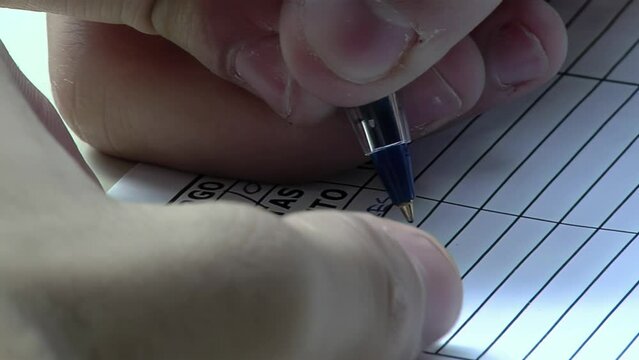 Hands of a Male High School Student Filling in a Form on Desk. Close Up. 