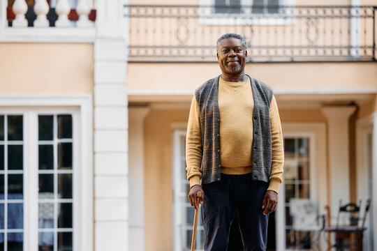 Smiling Black Senior Man Standing In Front Of Nursing Home And Looking At Camera.