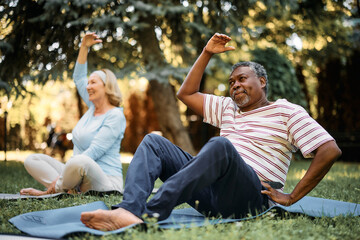 Black senior doing relaxation exercises during physical therapy class in nature.