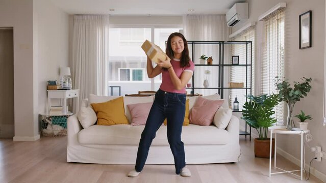 Asia people young Gen Z woman smile carry parcel box goods carton packaging happy joy fun dance at home. Omni channel enjoy buy gift order postal at retail online shop store fast courier send service.
