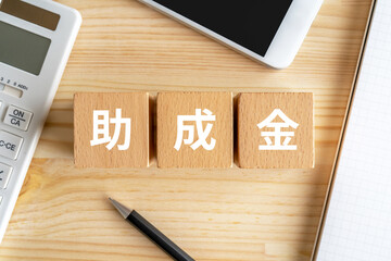 助成金と書かれたブロック、電卓、スマホ、ノート