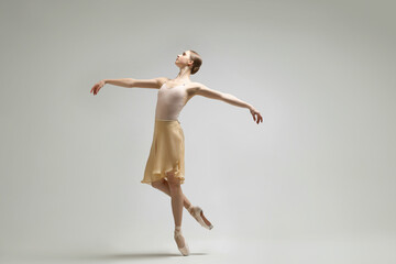 Young ballerina practicing dance moves on light grey background - obrazy, fototapety, plakaty