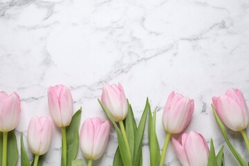 Beautiful tulips  on white marble table, flat lay. Space for text