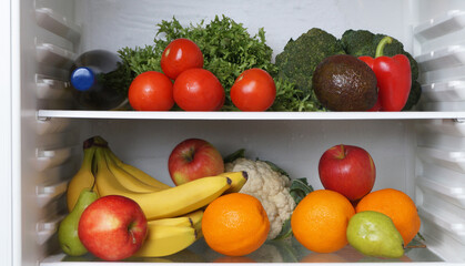 Fototapeta na wymiar Open refrigerator with many different fresh vegetables and fruits