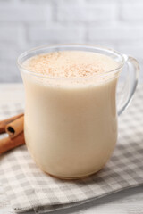 Delicious eggnog with cinnamon on wooden table, closeup