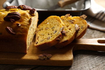 Cut pumpkin bread with pecan nuts on wooden table, closeup