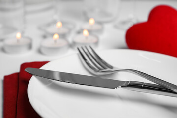 Beautiful table setting with burning candles on white table, closeup. Romantic dinner
