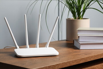 New white Wi-Fi router on wooden table indoors