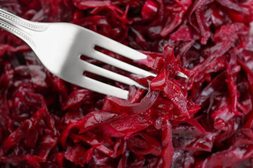 Fork with tasty red cabbage sauerkraut as background, closeup