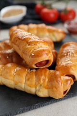 Delicious sausage rolls and ingredients on beige table, closeup