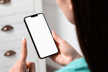 Woman holding smartphone with blank screen indoors, closeup. Mockup for design