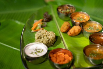 Fototapeta na wymiar A plate of different vegetarian dishes from the Andhra region in southern India, including fried potato dumplings ('aloo bajji') and spiced rice ('donne biryani').