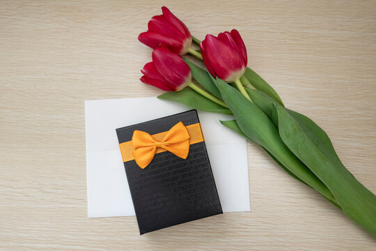 An Amazon gift card box with red tulip flowers. wooden table background.