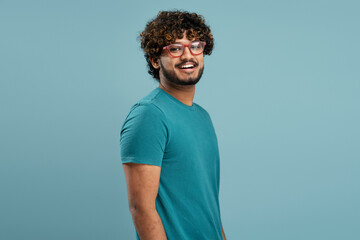 Young Indian man wearing stylish eyeglasses, smiling looking at camera, isolated blue background