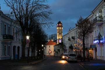 View of the old street in the historical center of the city and the fire tower in the background late in the evening with night lighting, Grodno, Belarus
