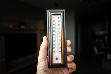 hand with a plastic mercury thermometer shows the temperature in room. Powerful heating in Russia....