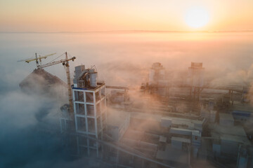 Aerial view of cement factory with high concrete plant structure and tower crane at industrial...
